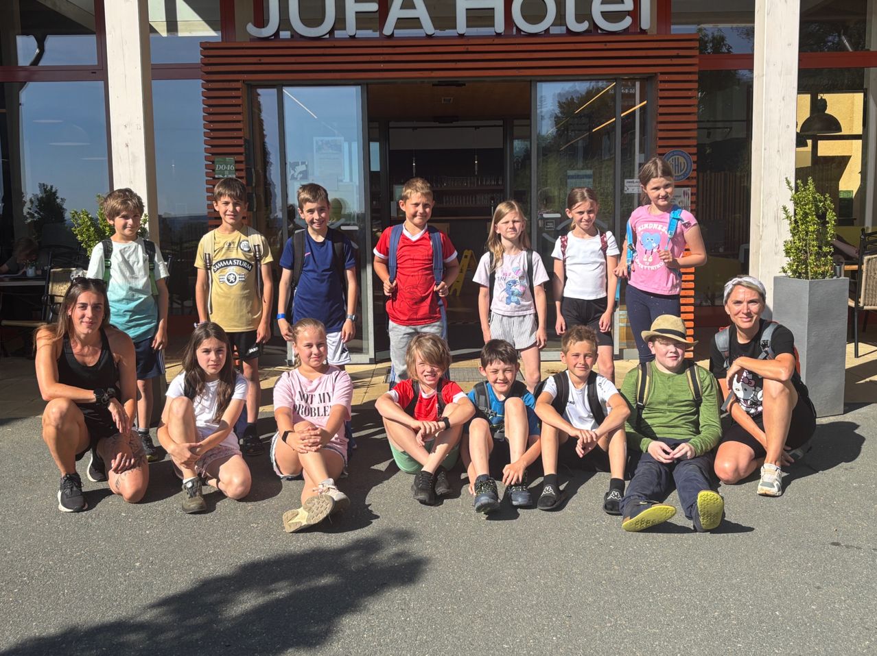 Gruppe von Kindern und Teenagern posiert für ein Foto vor dem J.U.E.A Hotel.
