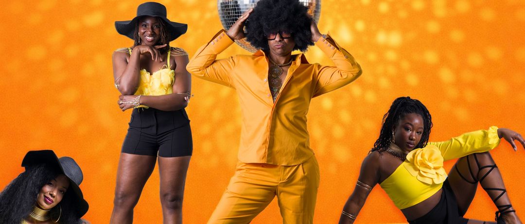Vier Personen in gelben Outfits posieren vor einem orangefarbenen Hintergrund. Ein Mann in Gelb steht, und drei Frauen sitzen oder stehen auf gelben Plattformen.