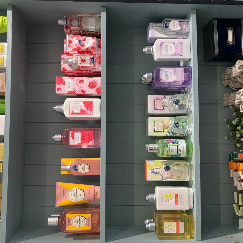 Ein Regal mit mehreren Flaschen Körperlotionen und -sprays. Jede Flasche hat ein anderes Design und eine andere Farbe.