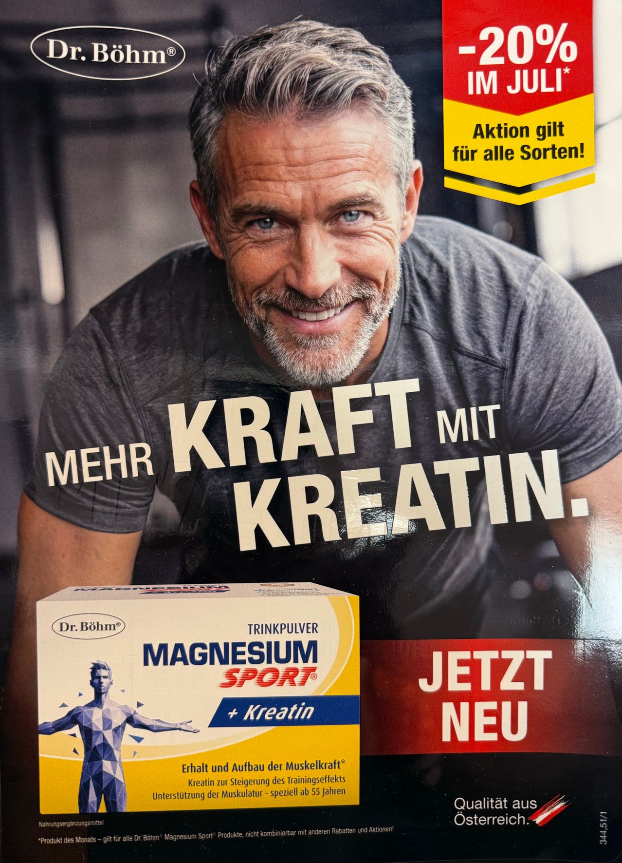 Ein lächelnder Mann in einem grauen T-Shirt mit den Worten 'Kraft mit Kreatin' über ihm, wirbt für eine Box 'Magnesium Sport' mit Kreatin.