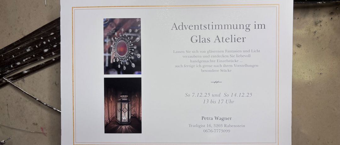 Eine weiße Einladungskarte zeigt zwei Bilder: eins eines Glasdesigns und ein anderes eines Laternen. Es steht 'Adventstimmung im Glas Atelier' mit Datum und Uhrzeit sowie einer Kontaktnummer.
