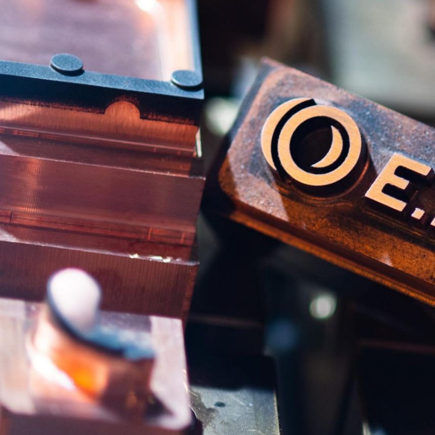 Eine Nahaufnahme von Kupferformen mit der Aufschrift O.E.L.T., Teil eines Herstellungsprozesses. Die Formen sind metallisch, kunstvoll gestaltet und in Reihen angeordnet.