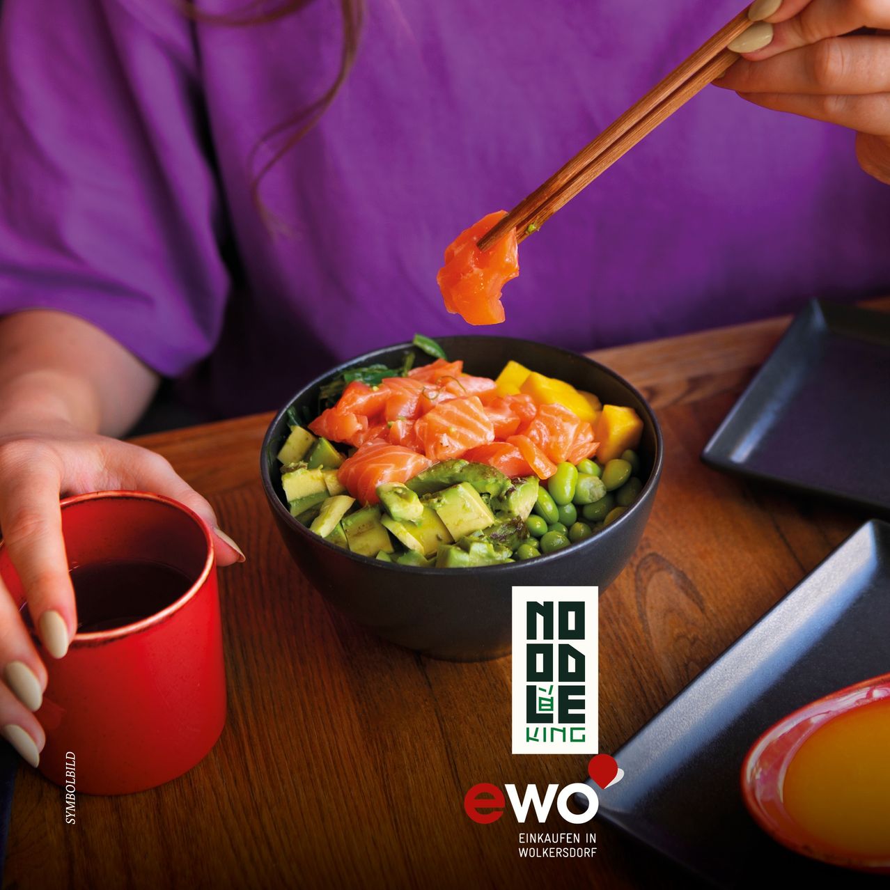 A person with chopsticks holding a piece of salmon above a bowl of mixed vegetables. A red cup is in the left hand.