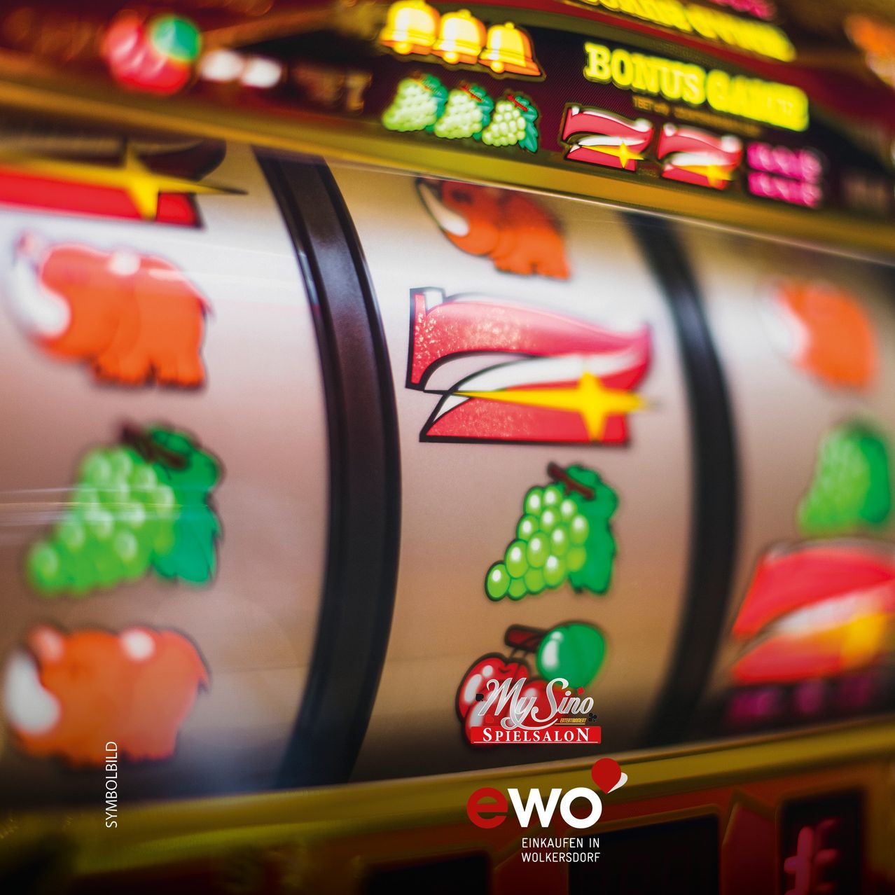 A close-up view of a slot machine with various fruit symbols, including grapes and cherries, on the reels. The machine has a golden border with the text 'My Sino Spielsalon' and 'Bonus Game'.