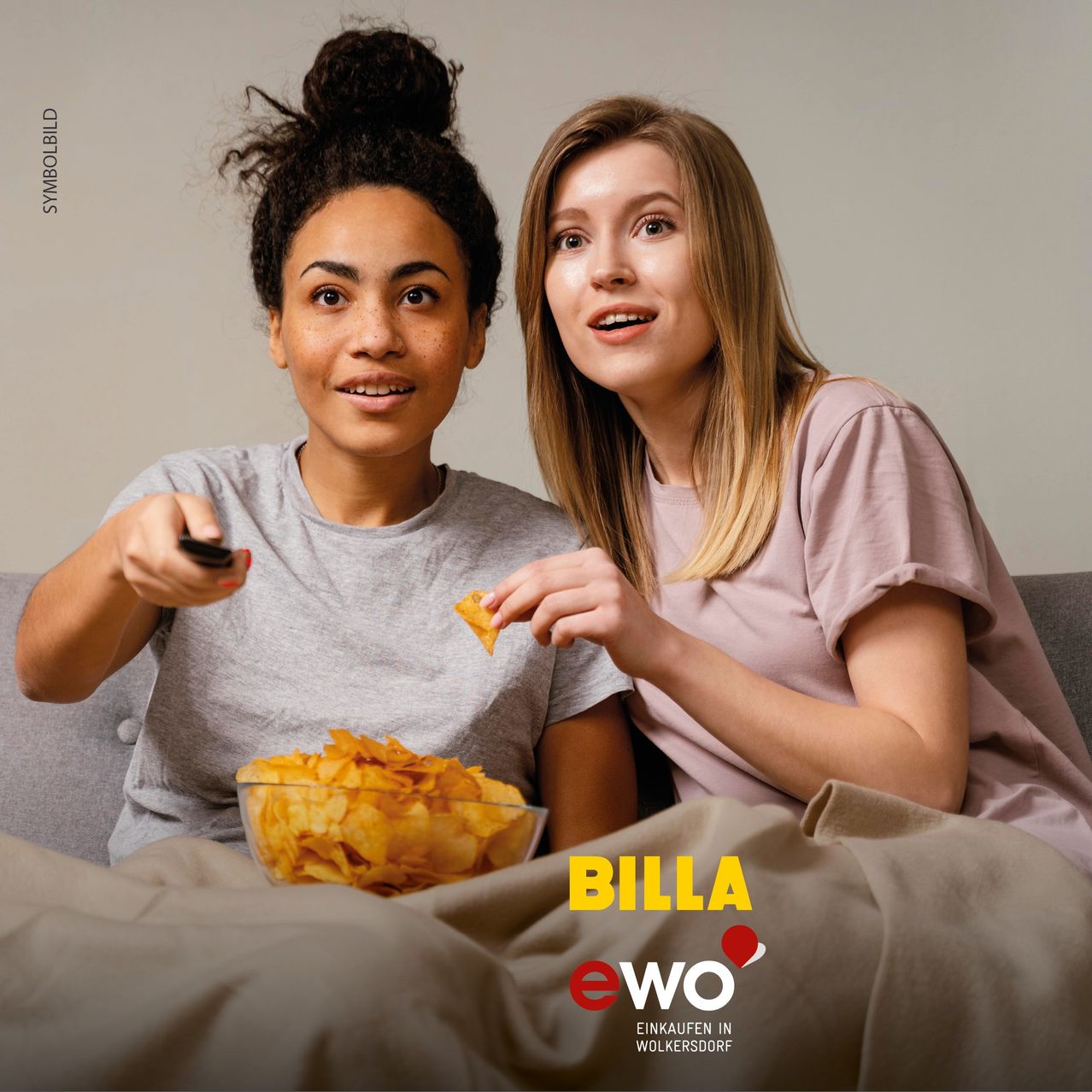 Zwei Frauen sitzen auf einer Couch, eine hält eine Fernbedienung und die andere isst Chips. Ein Teller mit Chips steht vor ihnen auf dem Bett. Das Bild hat einen Wasserzeichen mit dem Text 'BILLA eWO'.