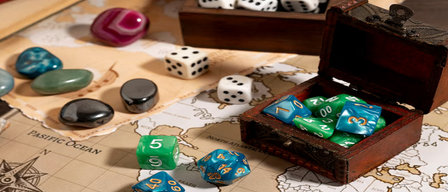 Ein Spieltisch zeigt Würfel, Steine und eine Schatztruhe auf einer alten Karte. Verschiedene Würfel mit Zahlen von 1 bis 20 sind verstreut.