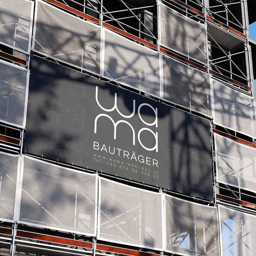 Ein Bauplatz mit einem großen Schild für 'WAMA BAUTRäGER' mit einem weißen und schwarzen Design, Kontaktdaten und einer Website-Adresse.