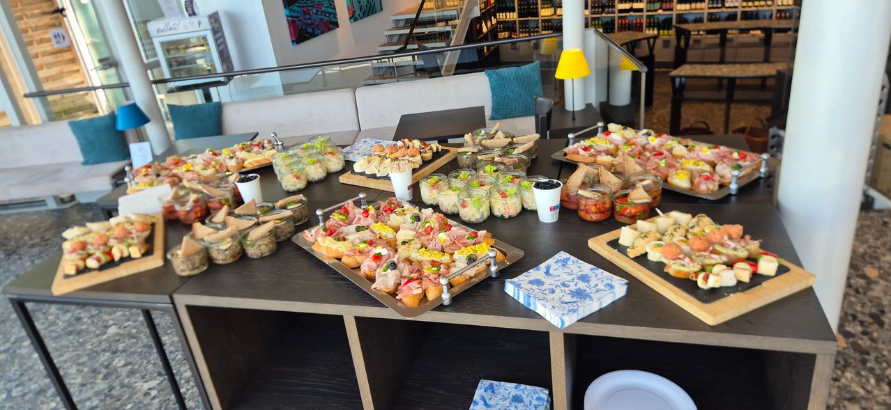 A table filled with various appetizers in jars and on trays, with decorative plates and a lamp.