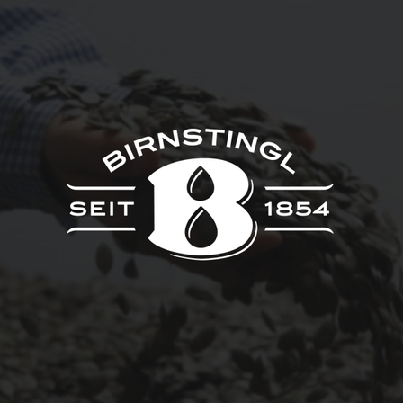 Eine Hand gießt Samen in Form eines B auf einem dunklen Hintergrund. Der Text 'BIRNSTINGL SEiT 1854' ist über dem B angezeigt.