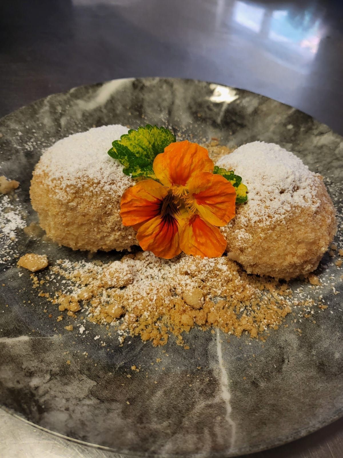 Zwei Donuts mit Puderzucker auf einem Teller, einer mit einer Blume und der andere mit einem Blatt.