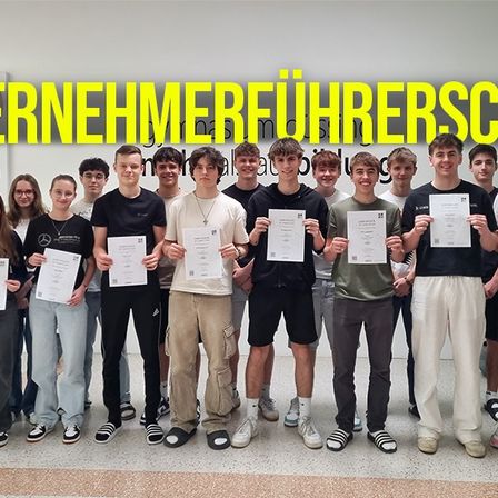 Eine Gruppe von Personen mit Zertifikaten posiert für ein Foto vor einer Wand mit Text in Deutsch.