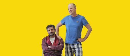 Ein Plakat für den Film Troma. Zwei Männer stehen vor einem leuchtend gelben Hintergrund. Einer sitzt auf einem Stuhl und der andere steht hinter ihm mit den Händen in den Hüften. Der Text auf dem Plakat lautet Freitag, 30.01.2026.