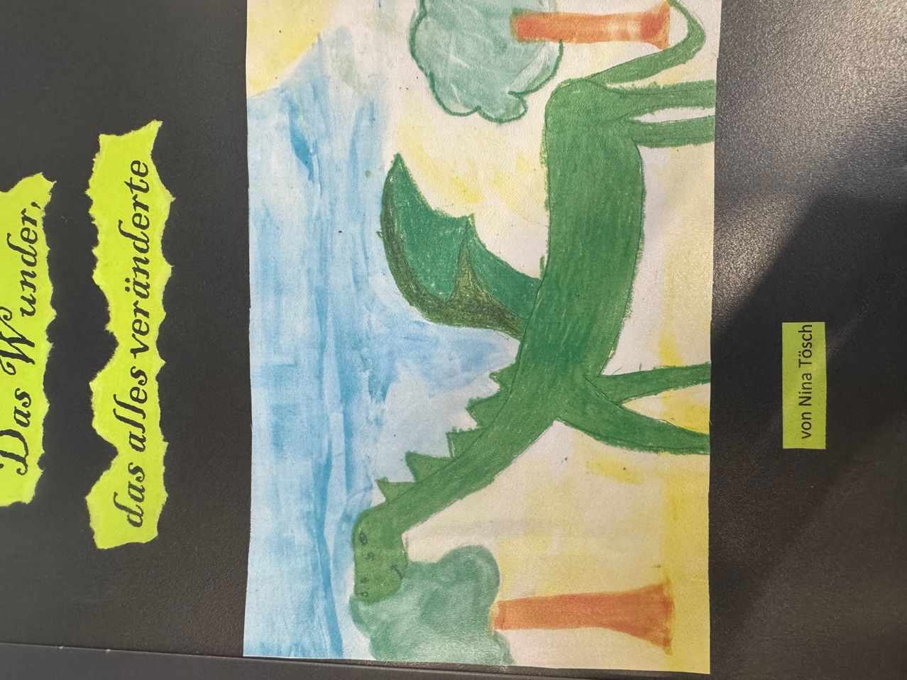 Ein Aquarellbild zeigt einen grünen Drachen mit gelbem Hintergrund und dem deutschen Ausdruck 'das alles vereinte' auf der linken Seite.