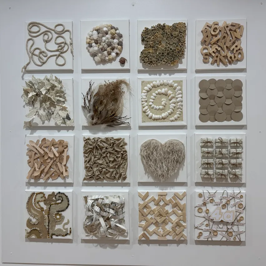 Eine Collage verschiedener Kunstwerke, die an einer weißen Wand ausgestellt sind. Jedes Stück ist einzigartig und aus Materialien wie Papier, Holz und anderen Gegenständen hergestellt. Die Sammlung umfasst komplizierte Designs und Muster.
