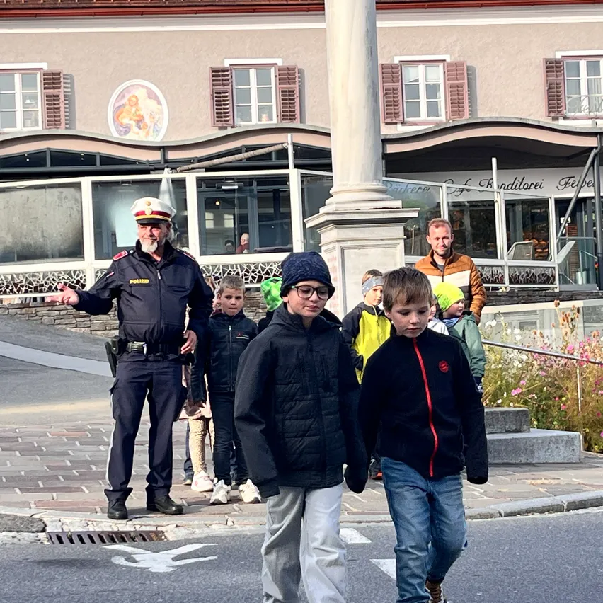 Ein Polizist leitet eine Gruppe von Kindern über die Straße.