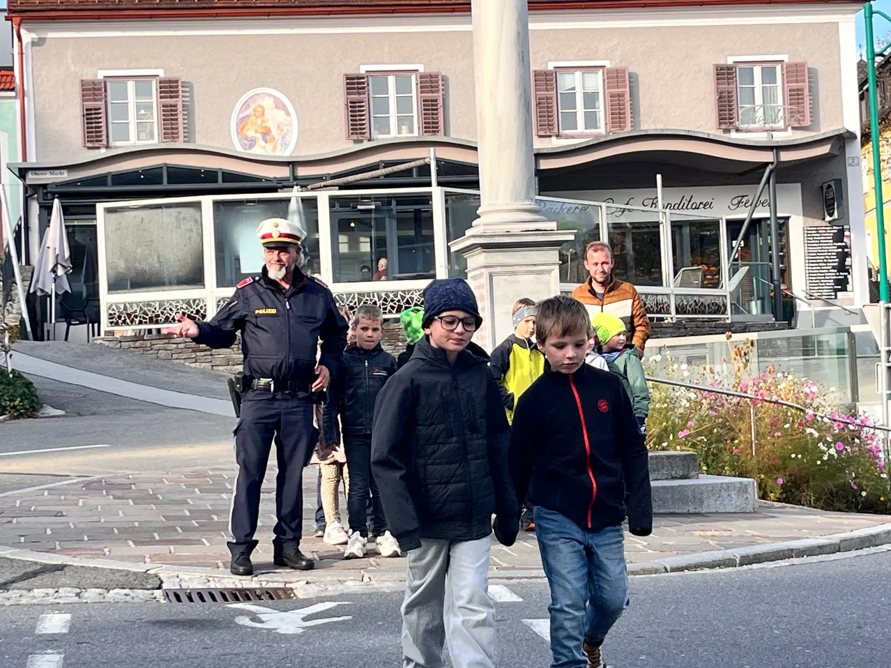 Ein Polizist leitet eine Gruppe von Kindern über die Straße.