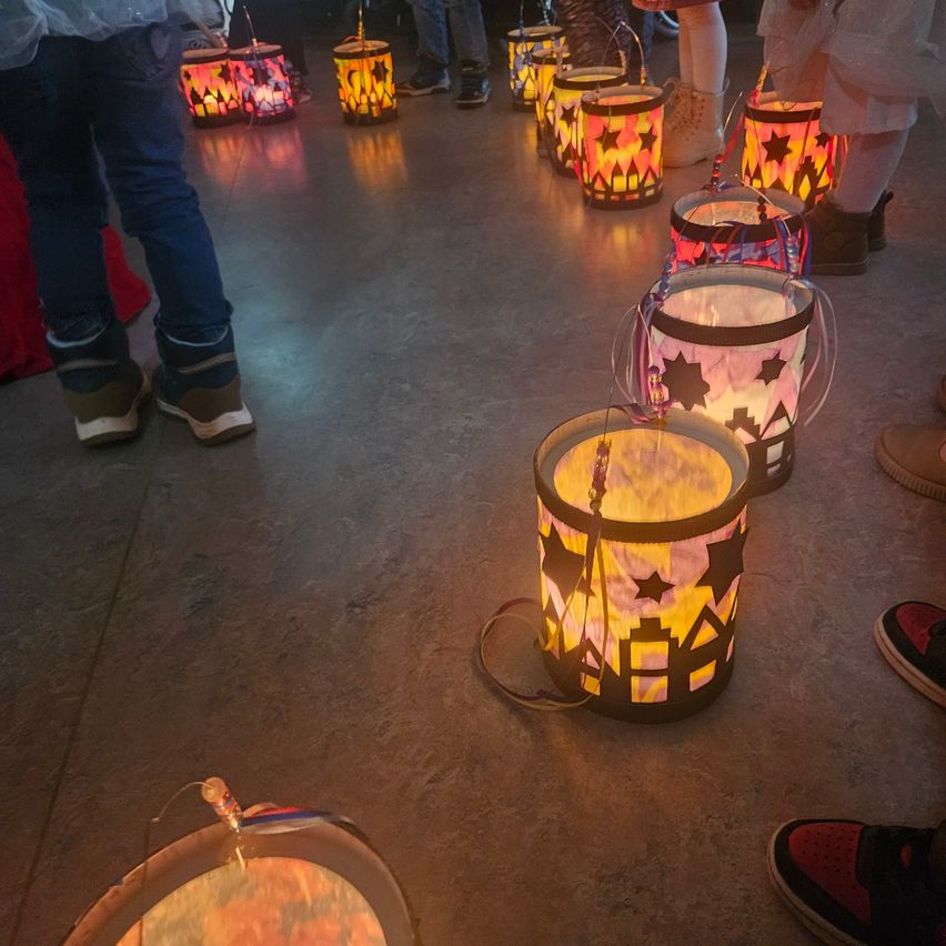 Eine Gruppe von Menschen mit brennenden Laternen in einer Reihe auf einem Betonboden stehend.