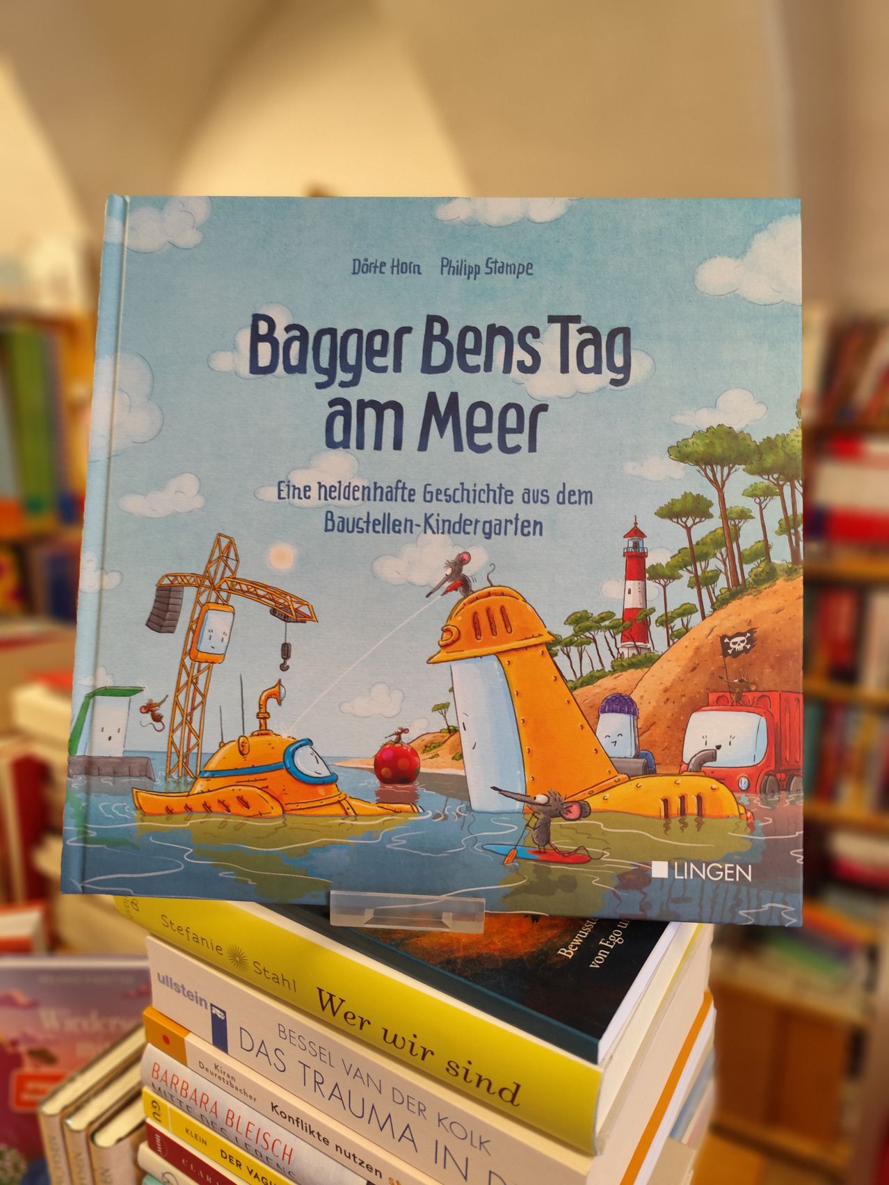 Das Buchcover zeigt ein U-Boot im Wasser, das von einem Kran angehoben wird, und einen Leuchtturm im Hintergrund. Der Titel lautet Bagger Bens Tag am Meer.