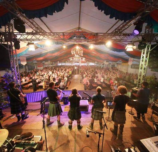 Eine Band spielt Instrumente auf der Bühne, während ein Publikum im Publikum sitzt.