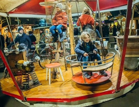 Eine Carousel-Fahrt mit rotem Dach steht auf einem Nachtmarkt, auf dem mehrere Menschen sitzen und zusehen.