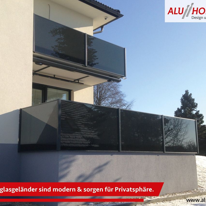 Ein Haus mit einem Glasbalkon an einem sonnigen Tag. Ein roter Banner mit der Aufschrift 'Glasgeländer sind modern und sorgen für Privatsphäre'.