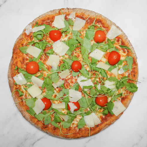 Eine runde Pizza mit roten Kirschtomaten, grünem Rucola und geriebenem Käse auf einer Marmoroberfläche.