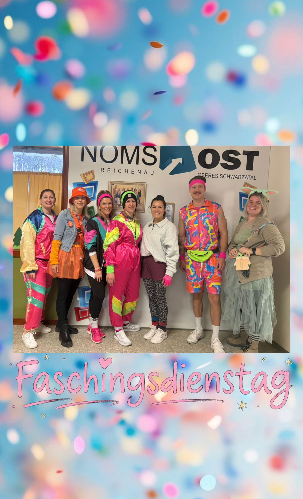 Eine Gruppe von Menschen in leuchtenden, farbenfrohen Kostümen posiert für ein Foto vor einem Schild, das 'Faschingsdienstag' steht. Sie lächeln und scheinen ein Ereignis zu feiern.