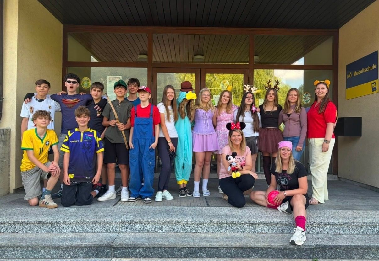 Eine Gruppe junger Menschen und Erwachsener in Kostümen posiert für ein Foto auf den Stufen eines Gebäudes. Die Kostüme reichen von Superhelden bis hin zu Disney-Charakteren.