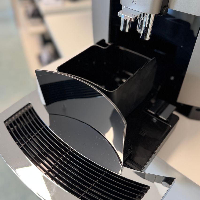Eine Nahaufnahme einer schwarzen und silbernen Kaffeemaschine mit Deckel, die ihr schlankes Design und polierte Oberfläche zeigt.