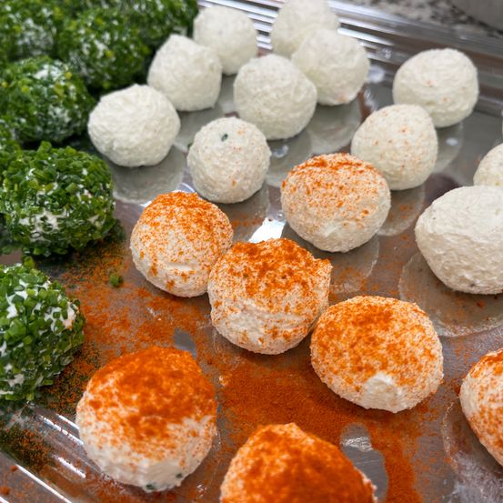 Ein Tablett mit verschiedenen runden Gerichten mit grünen und orangefarbenen Belägen. Die grünen haben eine Topping aus gehackten Schnittlauch, während die orangefarbenen eine Paprika-Sprinkling haben.