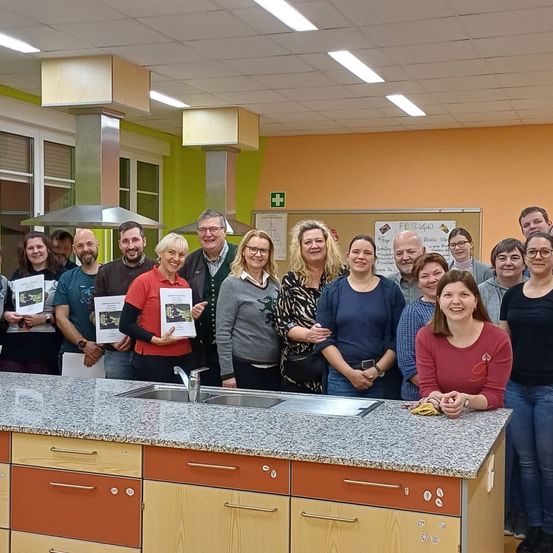 Eine Gruppe von Menschen mit Brille und lächelnd steht hinter einer Küchentheke und posiert für ein Foto.