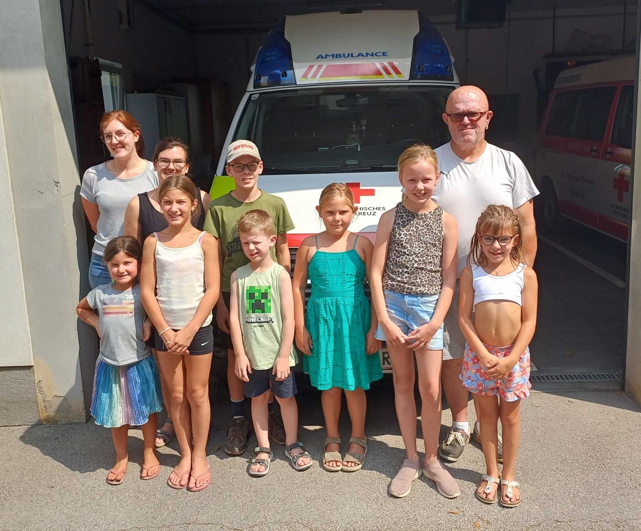 Eine Familie mit acht Personen, einschließlich Kindern und Erwachsenen, posiert für ein Foto vor einem Krankenwagen.