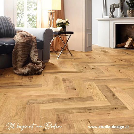 Ein gemütliches Wohnzimmer mit Holzboden, einem Sofa, einem Tisch mit Blumen, einer Lampe und einem Kamin mit einer Pferdestatue.