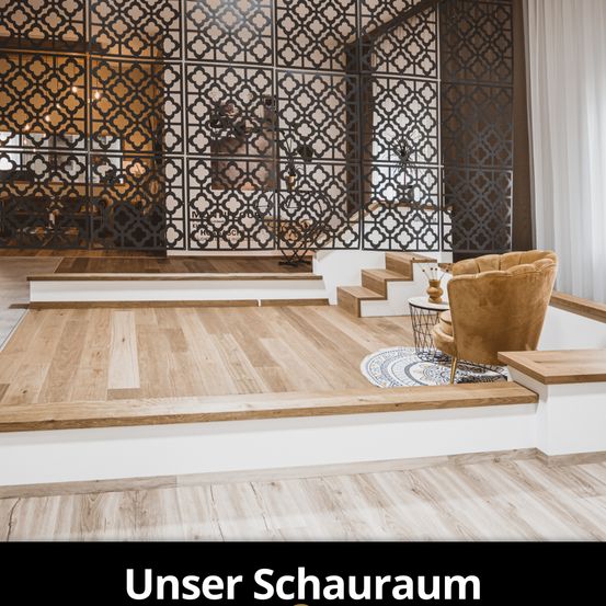 Innenansicht eines modernen Ausstellungsraums mit Holzböden, einem beigen Sessel und einer dekorativen Wand mit komplizierten Mustern. Der Raum verfügt über eine Treppe mit weißen Stufen und einem Metallgeländer.