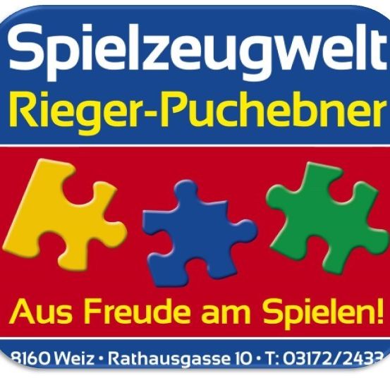 Ein blau-roter Schild mit weisser Schrift zeigt 'Spielzeugwelt Rieger-Puchebner', ein Puzzlestück-Logo und Kontaktdaten unten.