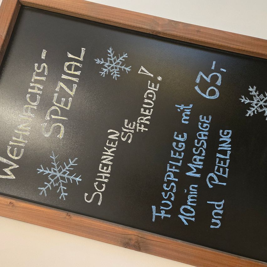 Ein Kreidetafel mit hölzerne Umrandung zeigt verschiedene Schneeflocken und bietet eine spezielle Fußmassage und Peeling-Behandlung für 63 Euro.