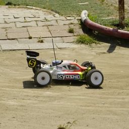 Ein ferngesteuertes Kyosho Rennauto mit der Nummer 5 auf einem unbefestigten Kurs.