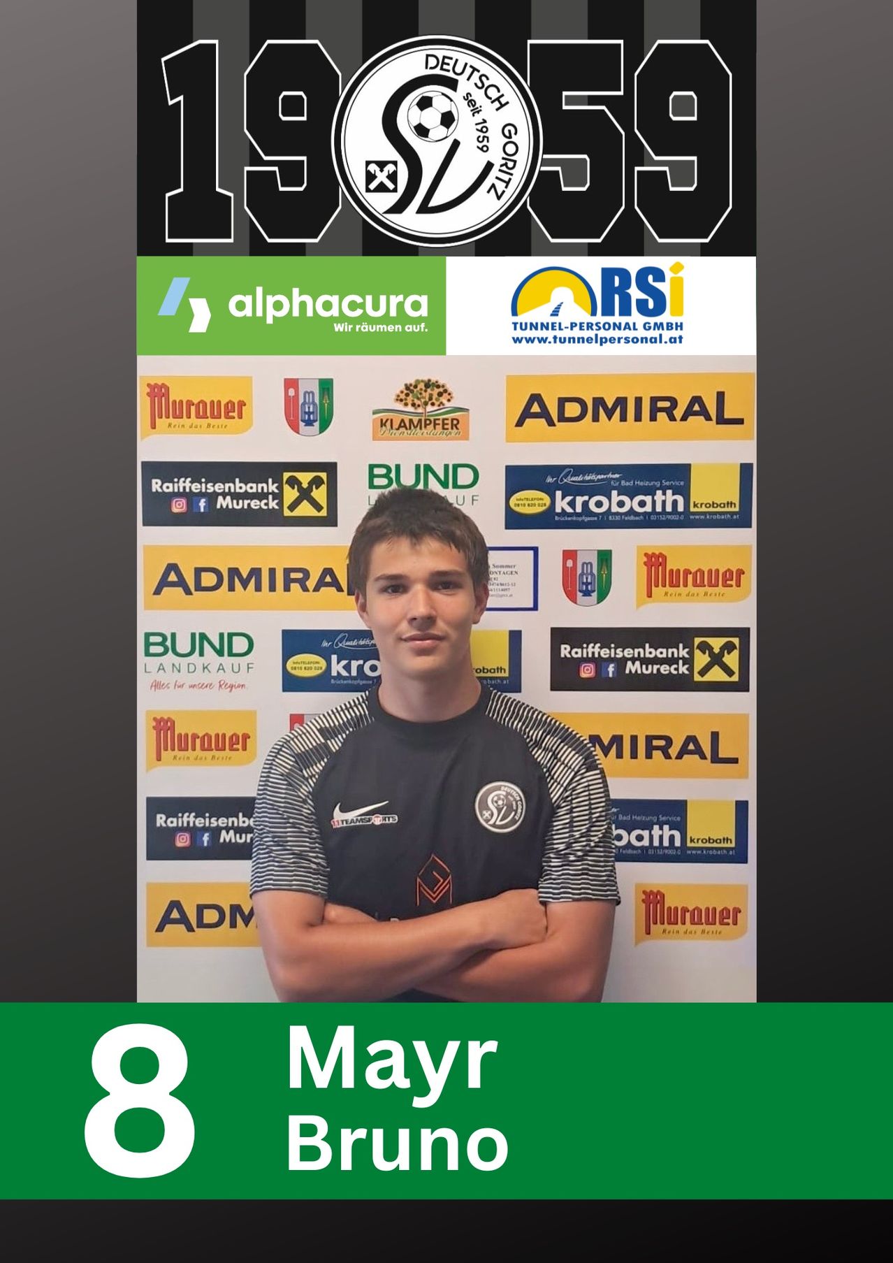 Ein Mann steht vor einem großen Banner mit mehreren Werbeanzeigen, trägt ein schwarz-weißes Fußballtrikot. Seine Arme sind gefaltet, und er scheint zu lächeln.