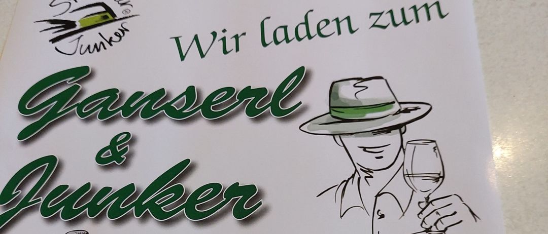 Ein Plakat für die Ganserle & Junker Veranstaltung, die jederzeit eingeladen wird. Es zeigt einen Mann mit Hut, der ein Weinglas hält, und erwähnt das Datum als 9. November 2025.