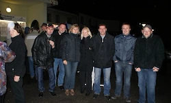 Eine Gruppe von Menschen in Winterkleidung posiert für ein Foto draußen bei Nacht.
