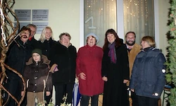 Eine Gruppe von Menschen, einschließlich Erwachsener und Kinder, steht lächelnd vor einem Fenster mit Dekorationen für ein Foto.