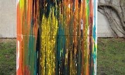 Ein abstraktes Gemälde mit leuchtenden Farben wie Rot, Gelb, Grün und Blau auf einem Rasen ausgestellt.