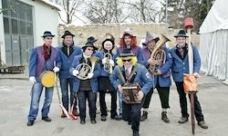 Eine Gruppe von Menschen in blauen Uniformen und Hüten posiert mit verschiedenen Musikinstrumenten vor einem Gebäude für ein Foto.