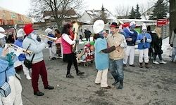 Eine Gruppe von Menschen in blauen und weißen Kostümen spielt Musikinstrumente und tanzt auf der Straße während eines Winterfestes.