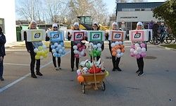Eine Gruppe von Menschen, die in Boxen gekleidet sind, die Ballons tragen und einen Wagen mit Gegenständen darin draußen.