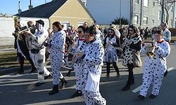 Eine Gruppe von Menschen in Dalmatiner-Kostümen, die mit Musikinstrumenten an einer Parade teilnehmen.