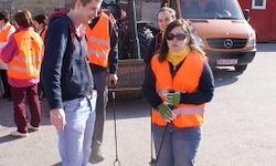 Eine Gruppe von Menschen in Sicherheitswesten steht draußen. Ein Mann und eine Frau stehen vorne. Ein Van ist hinter ihnen geparkt.