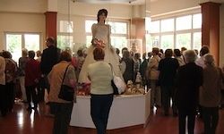 Eine Menschenmenge versammelt sich um eine große Hochzeitskleid-Statue, die in einem Raum mit großen Fenstern ausgestellt ist.