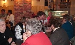 Eine Gruppe älterer Frauen sitzt an einem Tisch in einem gemütlichen, warm beleuchteten Restaurant. Sie scheinen in ein lebhaftes Gespräch vertieft zu sein.