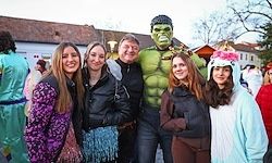 Fünf Menschen stehen vor einem Gebäude, lächeln und posieren für ein Foto. Eine Person ist als Hulk verkleidet.